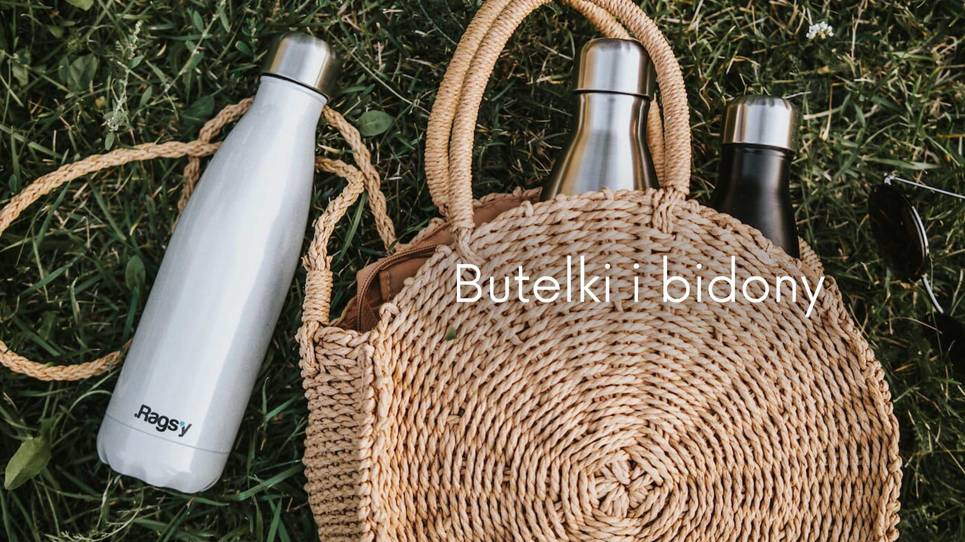 Butelki termiczne leżące na trawie, dwie butelki włożone do damskiej torebki.