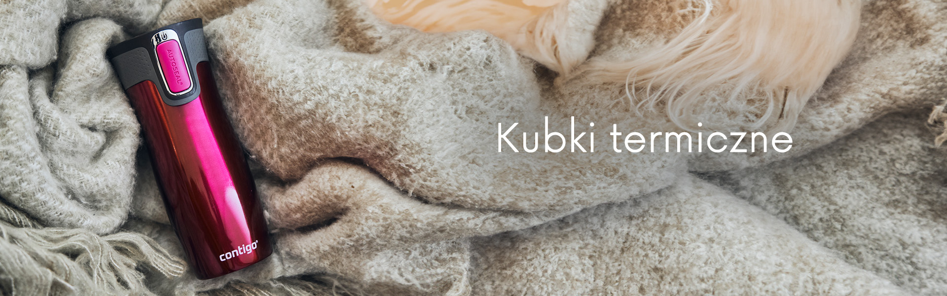 Kubek termiczny położony na kocu.